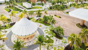Een resort met een centraal, rond plein, palmbomen en moderne architectuur.