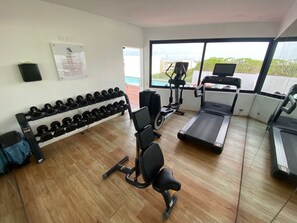 Ein Fitnessraum mit Laufband, Crosstrainer und Kurzhanteln.