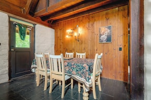 A wooden-paneled dining room with a table set for six, surrounded by chairs.