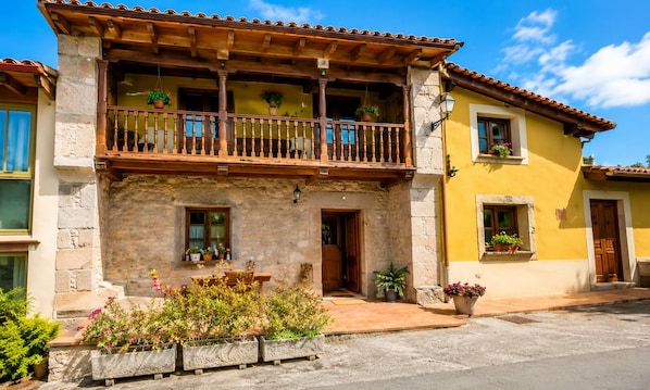 A two-story building with a balcony, stone facade, and potted plants. - Asturian House in Llanes - El Mayon del Cuetu Meré (Mere)