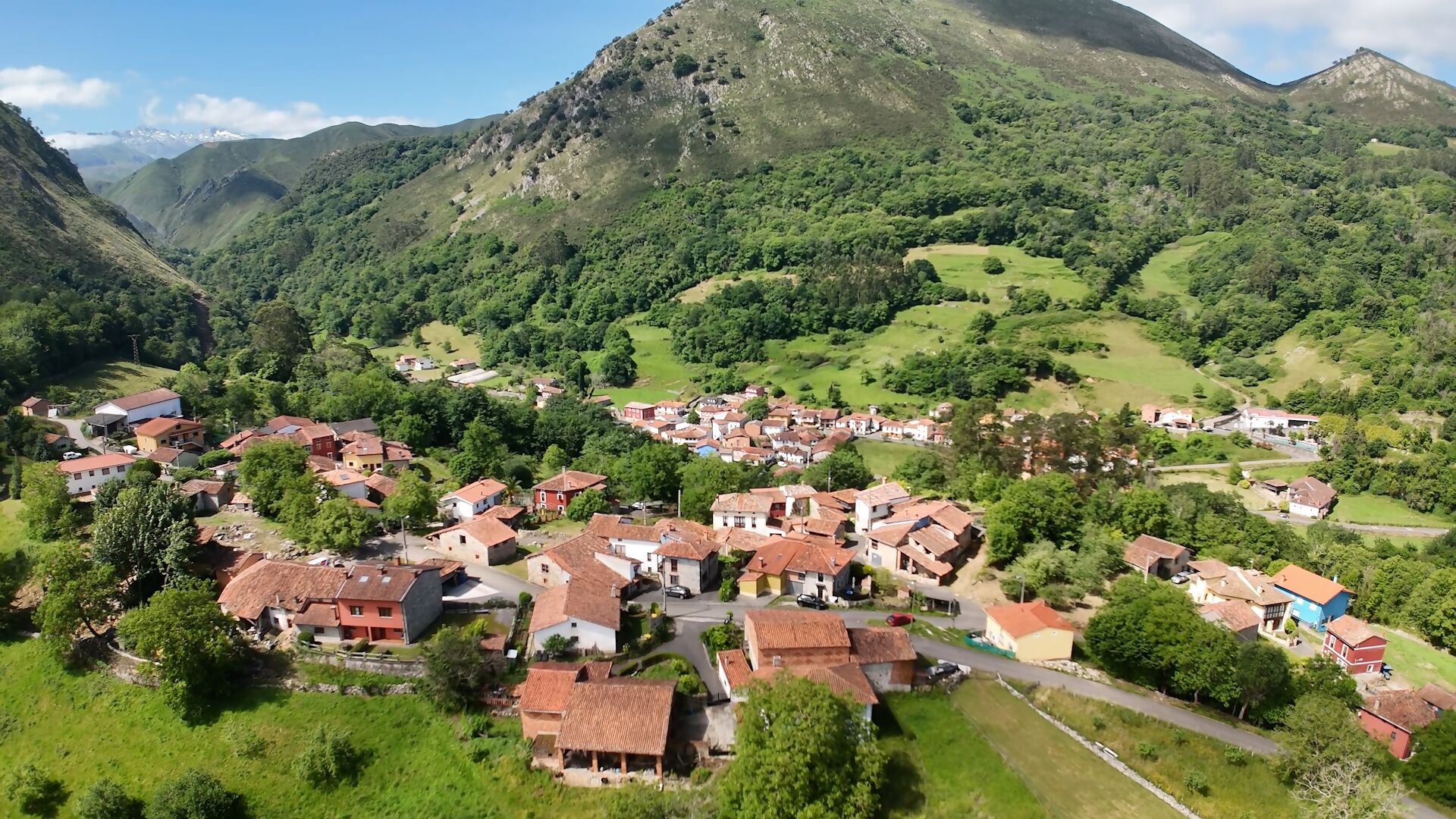 Un village dont les maisons sont entourées de verdure et de montagnes.