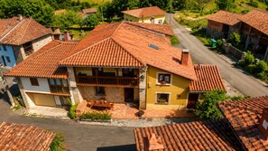A residential area with terracotta-tiled roofs, stone walls, and a paved road. - Asturian House in Llanes - El Mayon del Cuetu Meré (Mere)