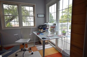 Une pièce avec un bureau, une chaise et de grandes fenêtres.