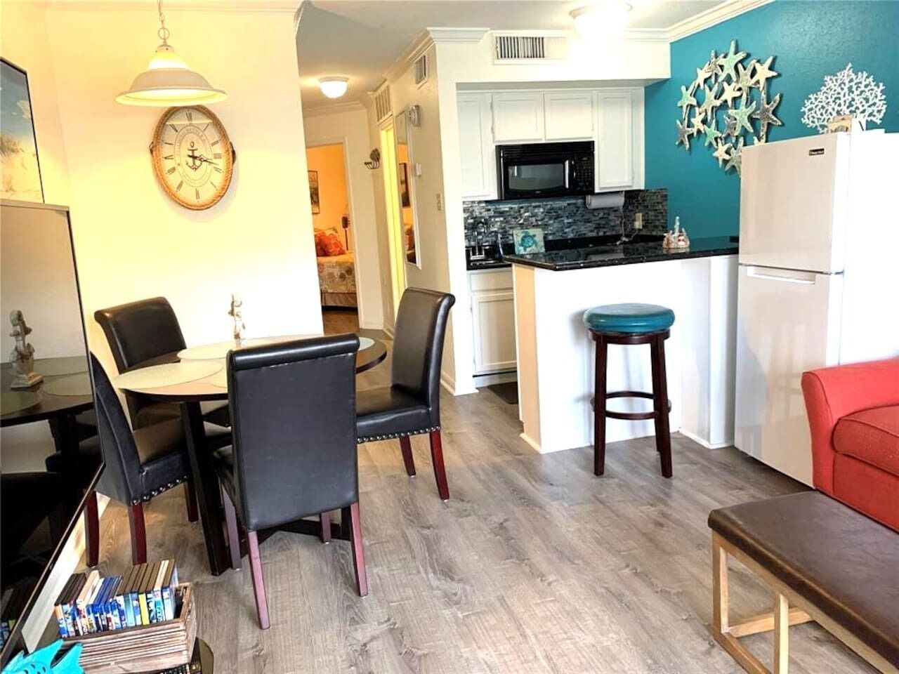 A compact kitchen with white cabinets, a black microwave, and a teal backsplash.