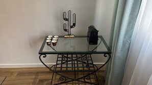 Ein Tisch mit Glasplatte und Metallgestell, ein Kaktus als Dekoration sowie mehrere Tassen.