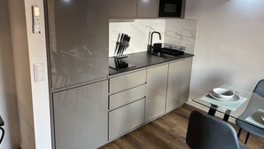 Eine moderne Küche mit Mikrowelle, Spüle und Essbereich mit Glastisch und Stühlen.