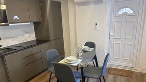 Une cuisine moderne avec une table à manger pour deux personnes, un four encastré et une porte blanche.
