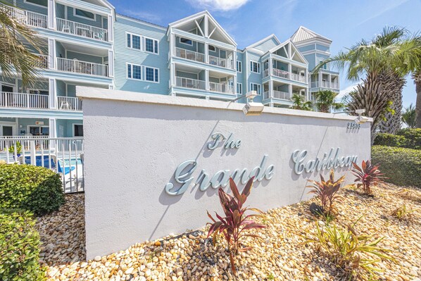 Ein mehrstöckiges Hotel mit Balkonen, einem Schild mit der Aufschrift 'The Grande Caribbean' und einem Poolbereich.