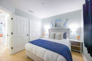 Ein Schlafzimmer mit Bett, Nachttischen, Kommode, einer Tür und einem an der Wand befestigten Spiegel.