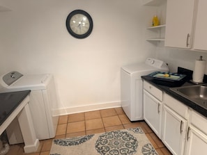 Een kleine keuken met een wasmachine, een klok en een spoelbak.