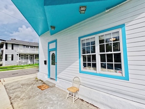 Ein zweistöckiges Haus mit Veranda, einer blauen Tür und einem Fenster mit blauem Rahmen.