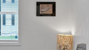 Una camera da letto con un letto, una finestra con persiane, una lampada a parete e un quadro incorniciato.