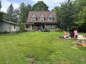 A house with a front porch, a lawn, and a deck with Adirondack chairs.