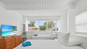 Une chambre avec une télévision, deux lits, une commode et une fenêtre donnant sur un beau paysage.