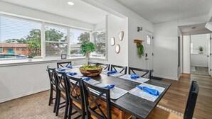 Un espace repas avec une longue table, des chaises et une plante servant de décoration centrale.