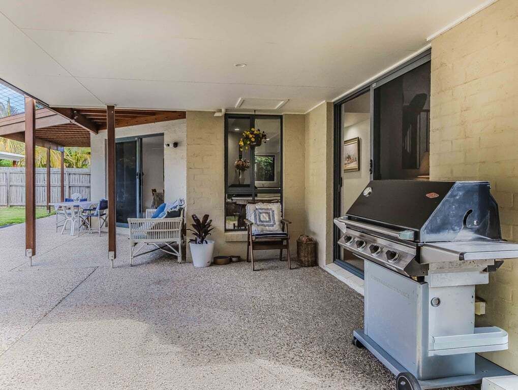 An outdoor patio with a barbecue grill, seating area, and a window with a view.