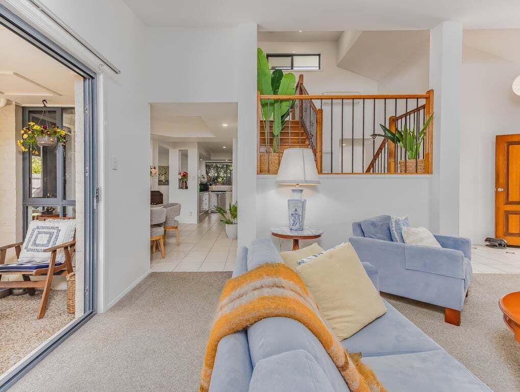 A modern living room with a sofa, a coffee table, and a staircase leading to an upper level.