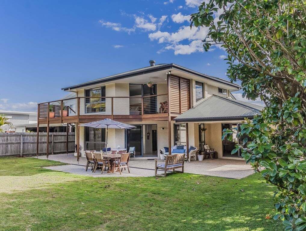 A two-story house with a patio, a covered outdoor seating area, and a fenced backyard.