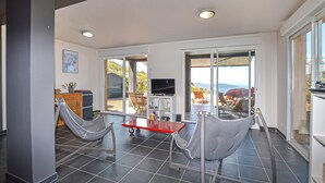 A modern interior with a dining area, a TV, and a view of the outdoors. - Lovely home in Appietto (Appietto)