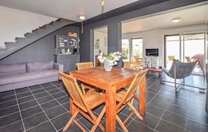 Ein stilvoller Wohnraum mit Essbereich, Sofa, Treppe und Fernseher.