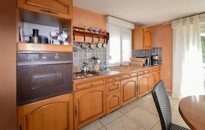 A kitchen with wooden cabinets, a Siemens oven, a gas stove, a coffee maker, and a window with curtains. - Nice home in MEZZAVIA with outdoor swimming pool (MEZZAVIA)