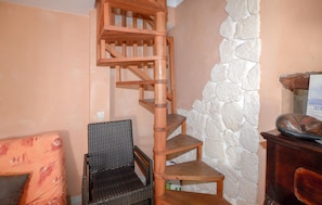 A corner room with a wooden spiral staircase, a wicker chair, and a stone wall. - Nice home in MEZZAVIA with outdoor swimming pool (MEZZAVIA)