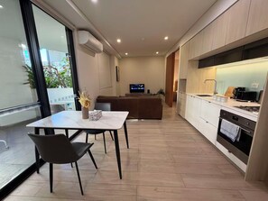 Eine moderne Küche mit Essbereich, einem Fernseher und Blick durch eine Glastür.