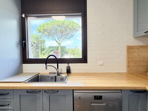 Una cocina con ventana, pileta y lavavajillas.