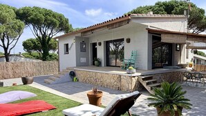 Eine moderne Villa mit Terrasse, Gartenmöbeln und einer Steinmauer.