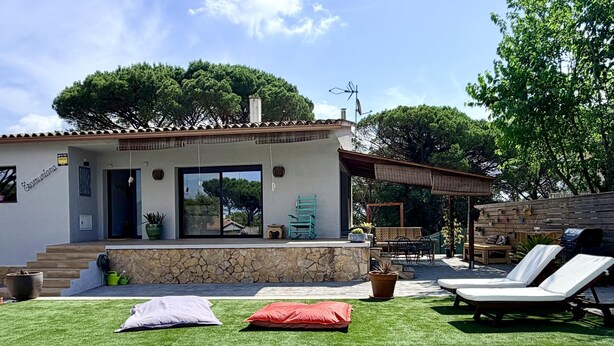 Ein modernes Haus mit Swimmingpool, Sitzgelegenheiten im Freien und einer Steinfassade.