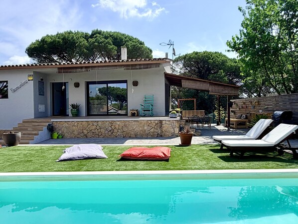 Una casa moderna con piscina, mobiliario exterior y fachada de piedra.