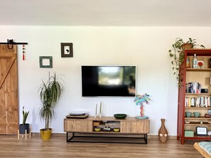 Ein Wohnzimmer mit einer Holz-TV-Kommode, einem Bücherregal und einer großen Pflanze.