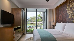 A hotel room with a bed, a TV, a ceiling fan, and a view of a pool and buildings. - Marriott Bali Nusa Dua Gardens 1 Bedroom Kitchenette 3 weeks (Badung Regency)