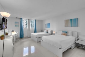 Habitació d'hotel moderna amb dos llits, un escriptori amb una làmpada i obres d'art a les parets.