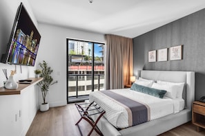 A modern bedroom with a large bed, a TV, a desk, and a balcony with a city view. - Bright & Modern Brickell Retreat-Prime Location- 7th Floor (Miami)