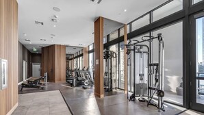 Et moderne fitnesscenter med træningsudstyr, store vinduer og en lys, rummelig indretning.