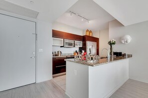 A modern kitchen with a central island, stainless steel appliances, and a decorative vase. - High-Floor Bay View Retreat at The Plaza Brickell (Miami)