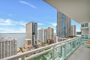 A high-rise building with a modern architectural design, a balcony with a glass railing, and a view of the cityscape and water. - High-Floor Bay View Retreat at The Plaza Brickell (Miami)
