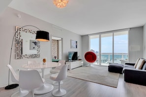 A modern living room with a dining area, large windows, and a city view. - High-Floor Bay View Retreat at The Plaza Brickell (Miami)