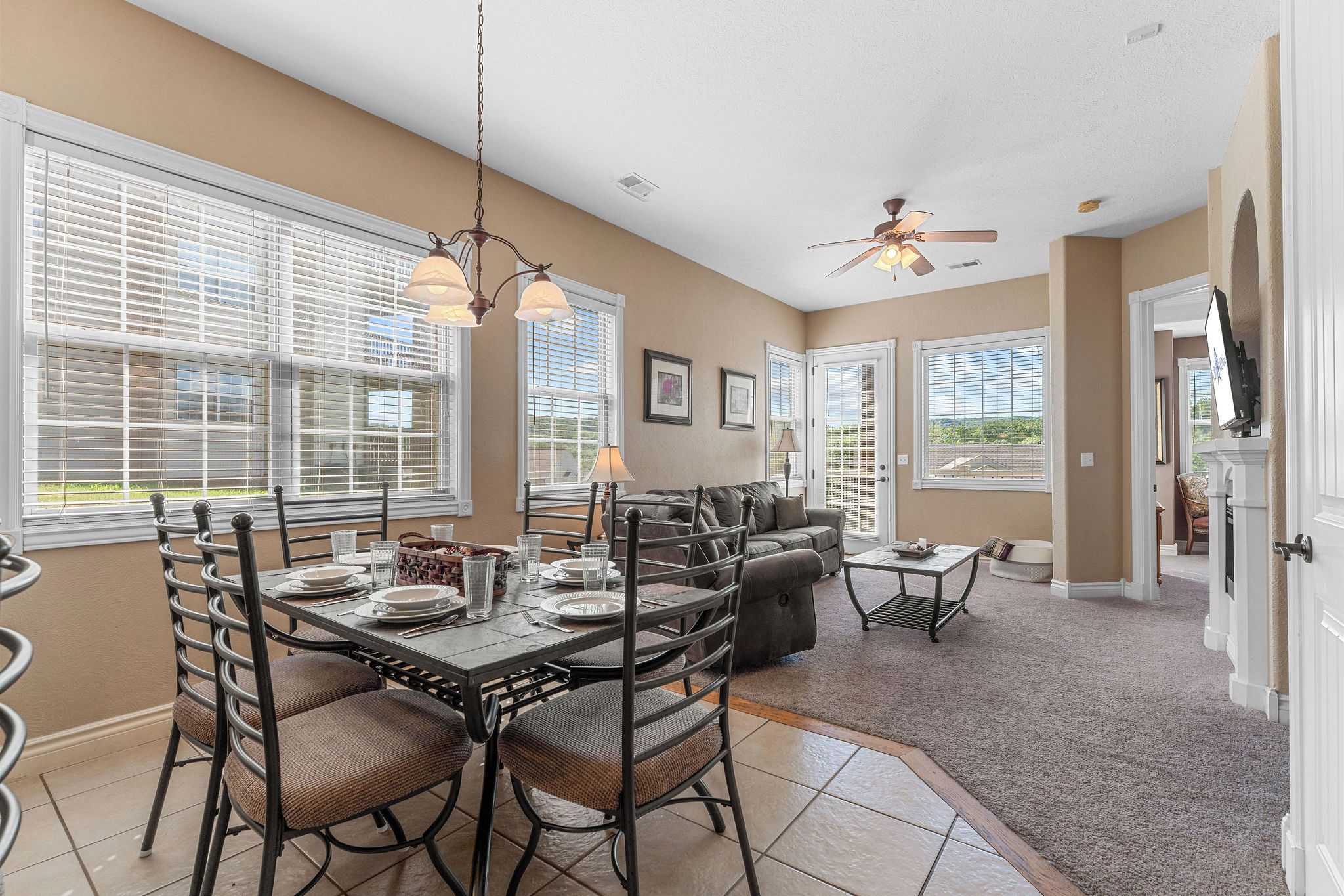 A spacious living area with a dining table set for four, a sofa, and a television mounted on the wall.
