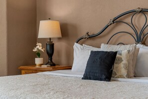 A neatly made bed with a patterned bedspread, a bedside lamp, and a small vase with flowers. - Condo Mins to Silver Dollar City w Free Tickets_Outdoor Pool_Tennis Courts_Water Path (Branson)