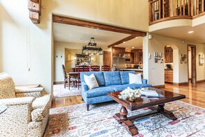 Ein großzügiges Wohnzimmer mit blauem Sofa, Holztisch und gemusterten Teppichen.