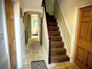 A hallway with a carpeted staircase, wooden doors, and a tiled floor. - Beautiful 3 Bed Cottage in the Heart of Pembroke (Pembroke)