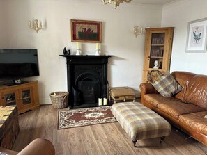 Ein Wohnzimmer mit Kamin, Fernseher, Sofa und Bücherregal.