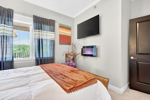 Un dormitorio con cama, cortinas, televisor, puerta y ventana con persianas.
