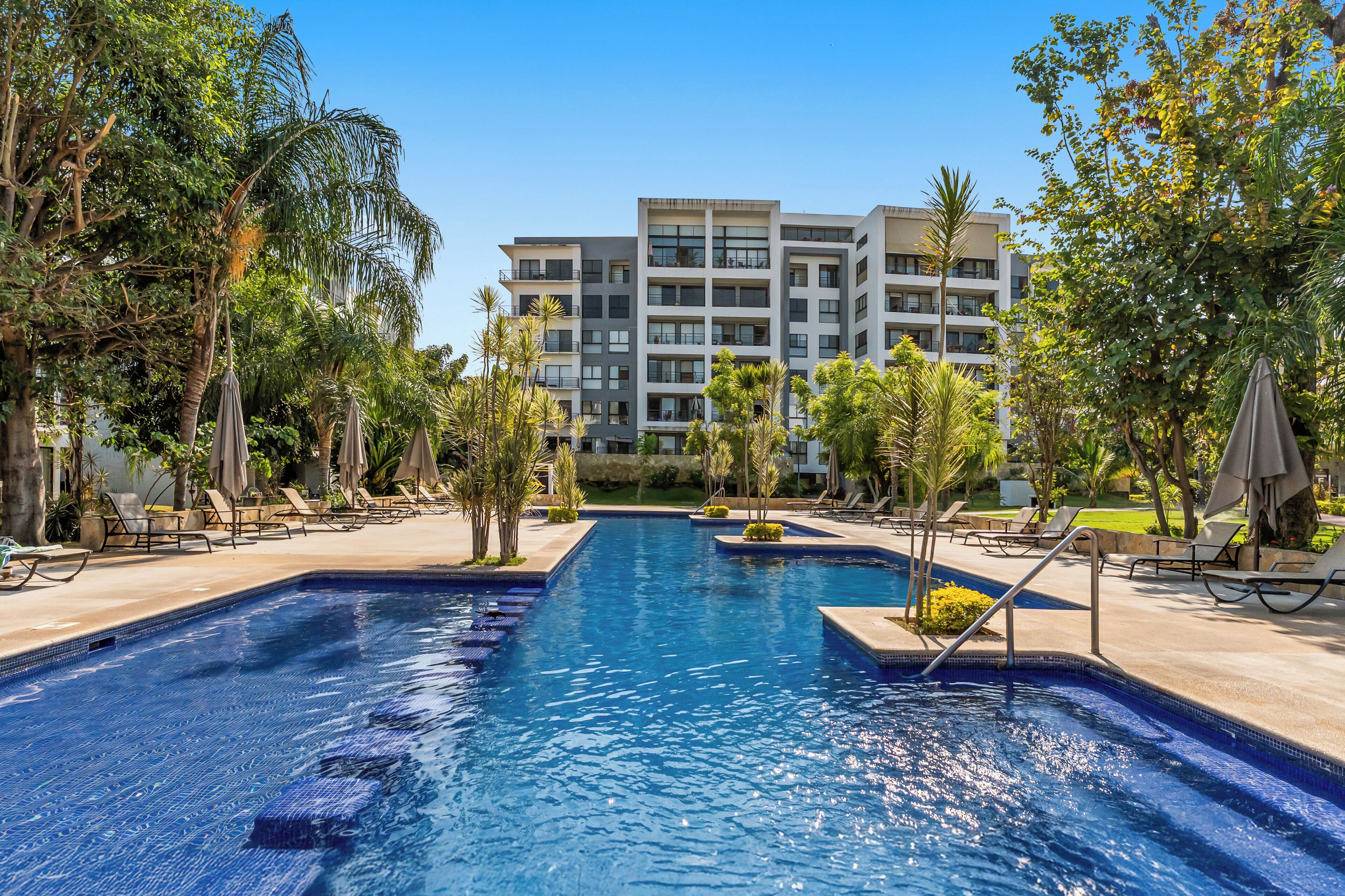 Una piscina al aire libre, sombrillas, sillones reclinables de piscina