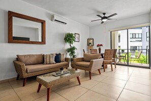 Ein Wohnzimmer mit einer Couch, Sesseln, einem Couchtisch und einem Deckenventilator.