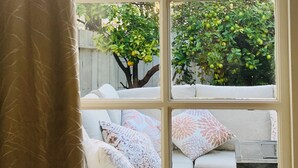 Ein Zimmer mit großem Fenster, einer Couch mit gemusterten Kissen und einem kleinen Tisch.