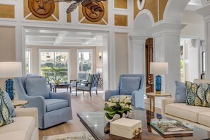 A spacious living room with a high ceiling, a glass coffee table, and a view of the outdoors. - Serene Saltwater Sanctuary | Inlet #607 (New Smyrna Beach)