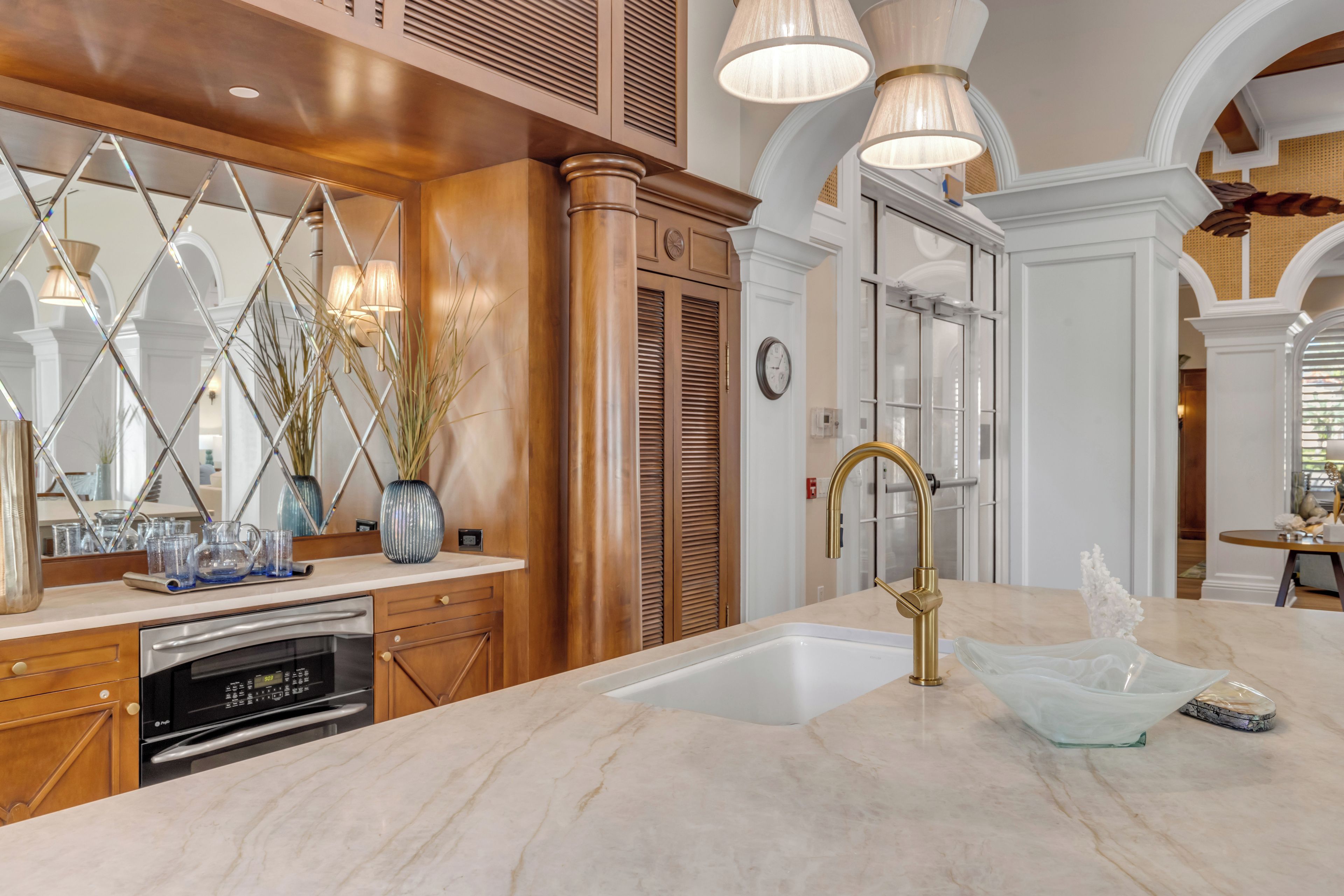 A kitchen with a marble countertop, stainless steel appliances, and a gold faucet.